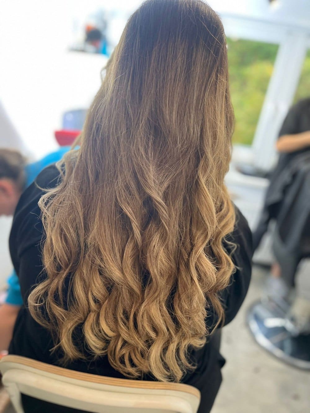 Długie włosy z balayage, od ciemnych odrostów po jasne, karmelowe końce